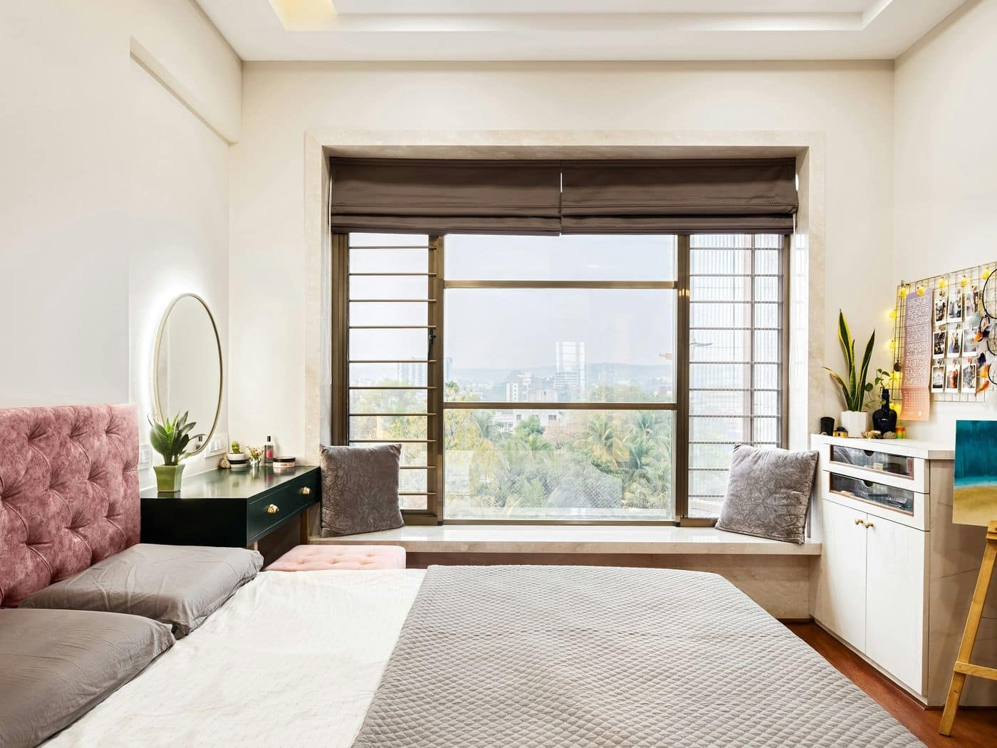 Bright bedroom with marble window seat, tufted pink headboard, dressing desk, storage unit and art easel