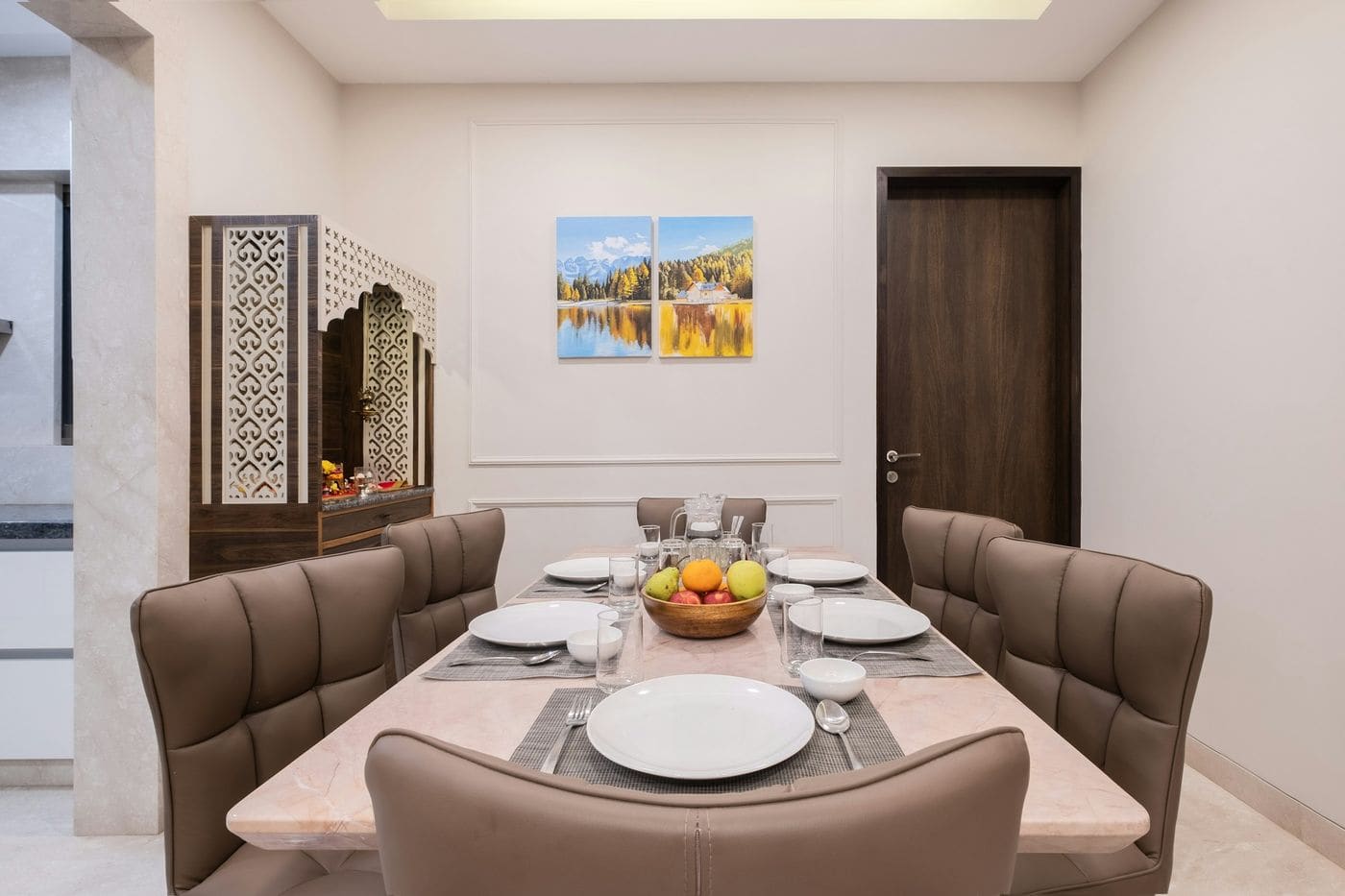 Indian dining room with marble-top table, upholstered chairs, carved jali puja unit and panelled wall